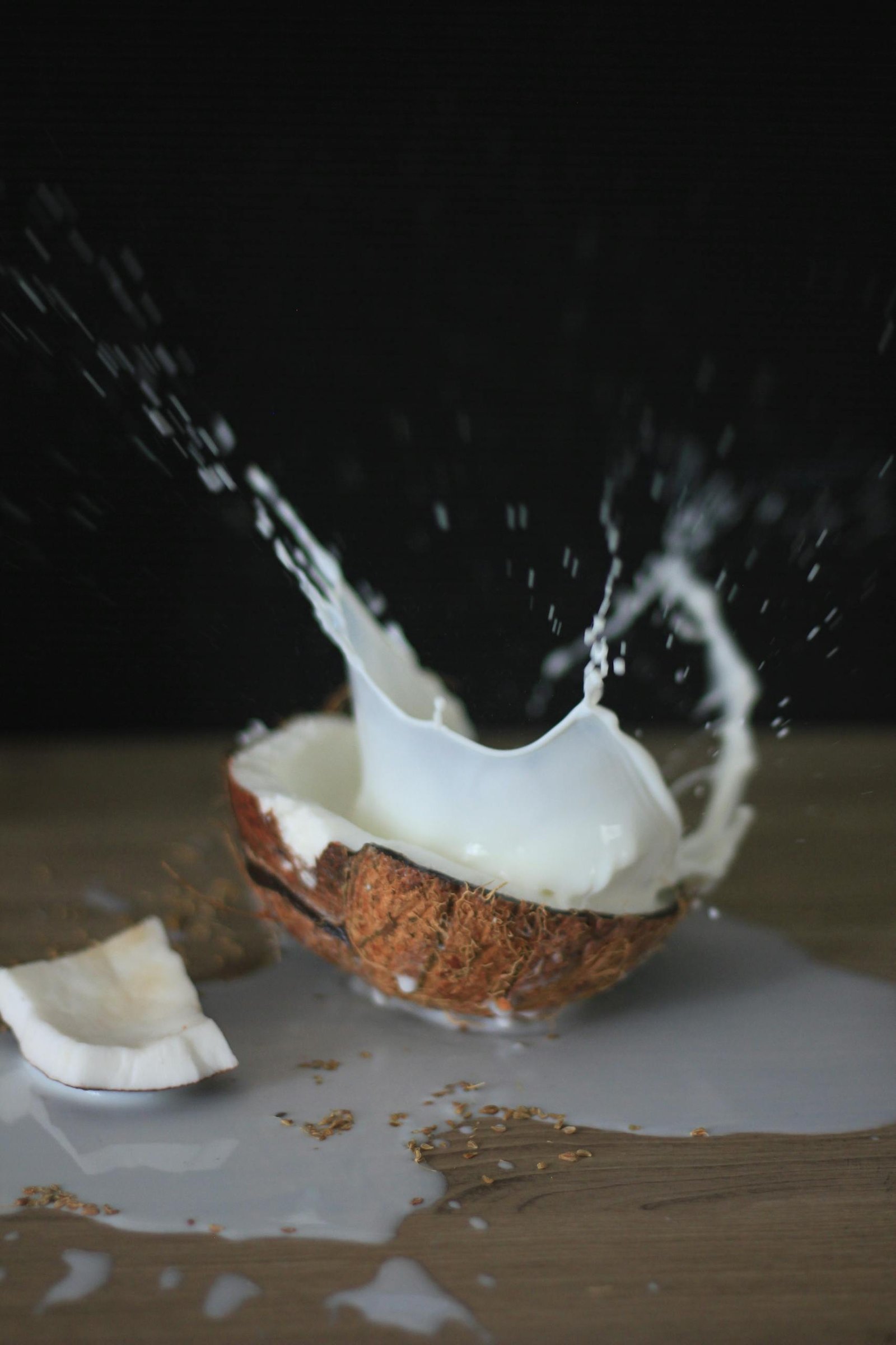 A coconut halves with milk splashing in a dynamic still life shot.